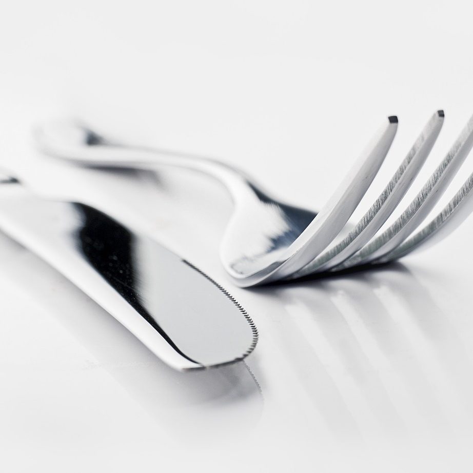 Photo of a butter knife and fork on a grey surface