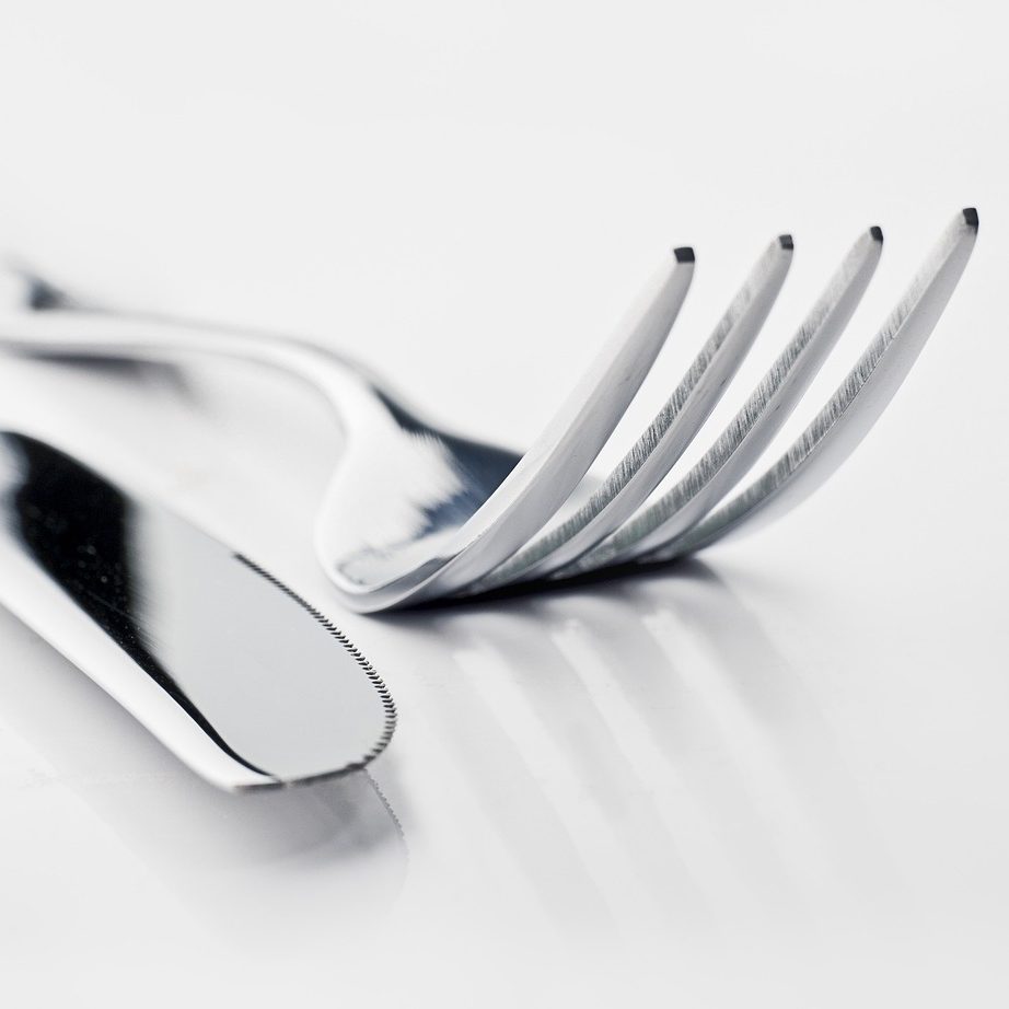 Photo of a silver knife and fork on a white surface.