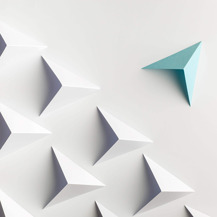geometric 3D white arrows/triangles in a pattern, with a random teal arrow arranged differently to stick out.