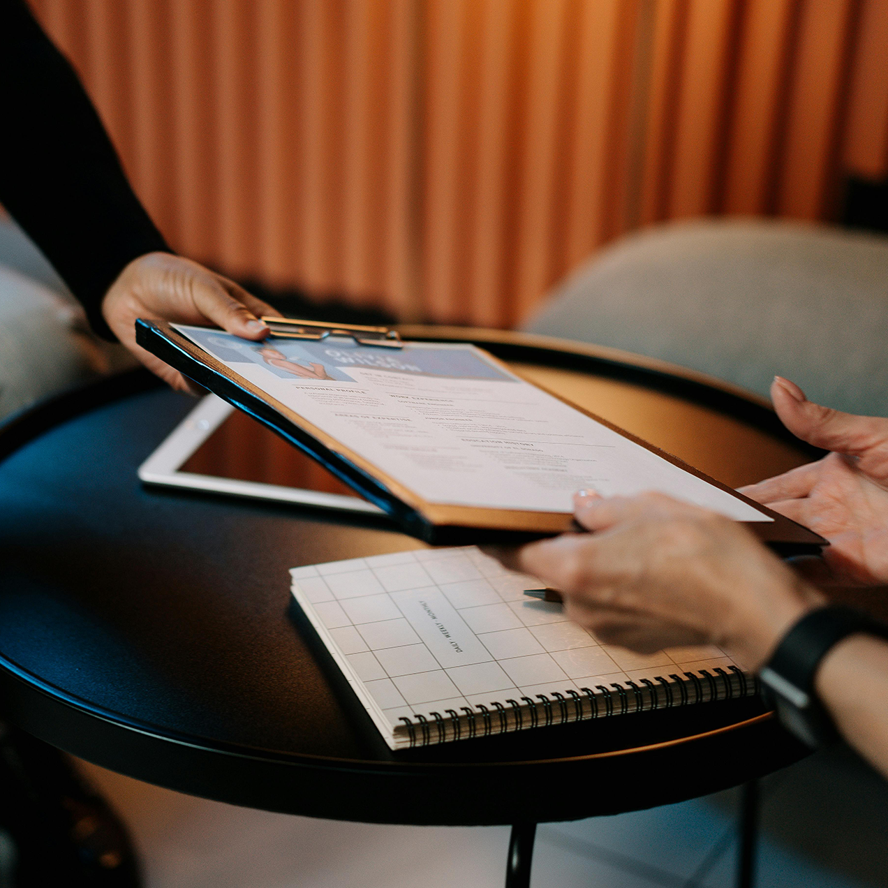 Photo of a handoff of a resume on a clipboard.